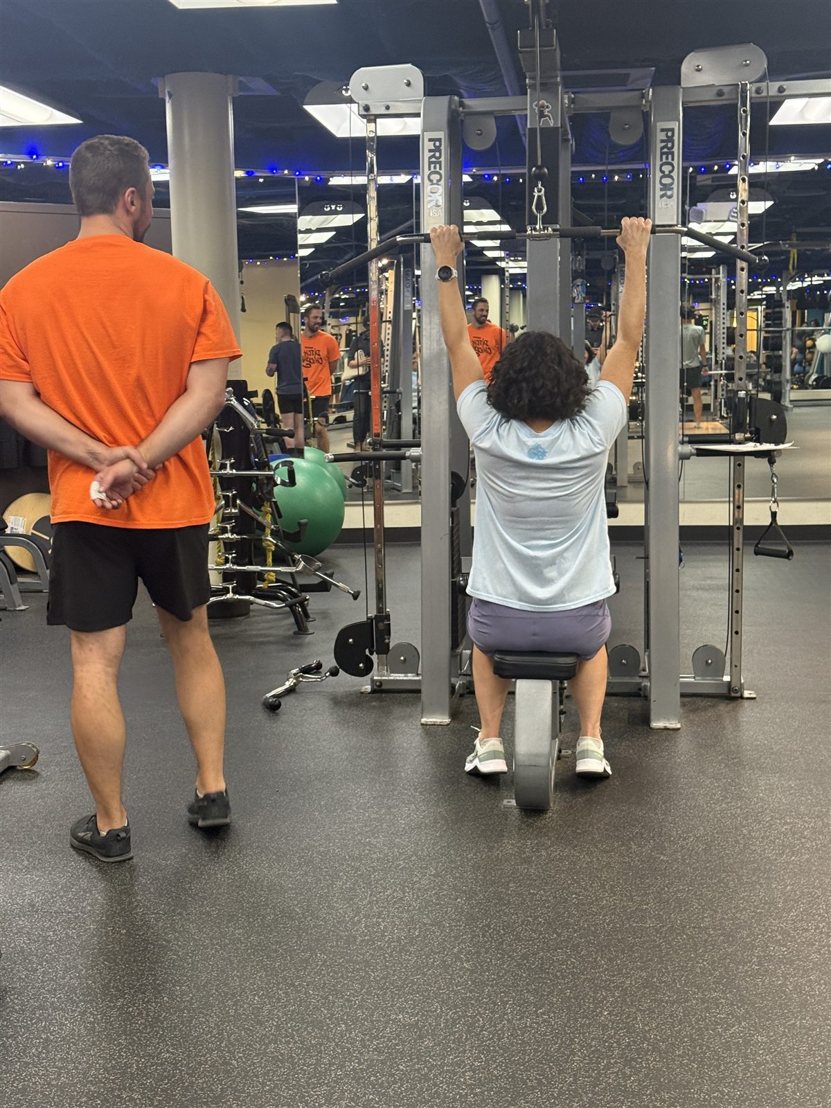 A ONE Boulder Fitness trainer coaching a member through a lat pulldown