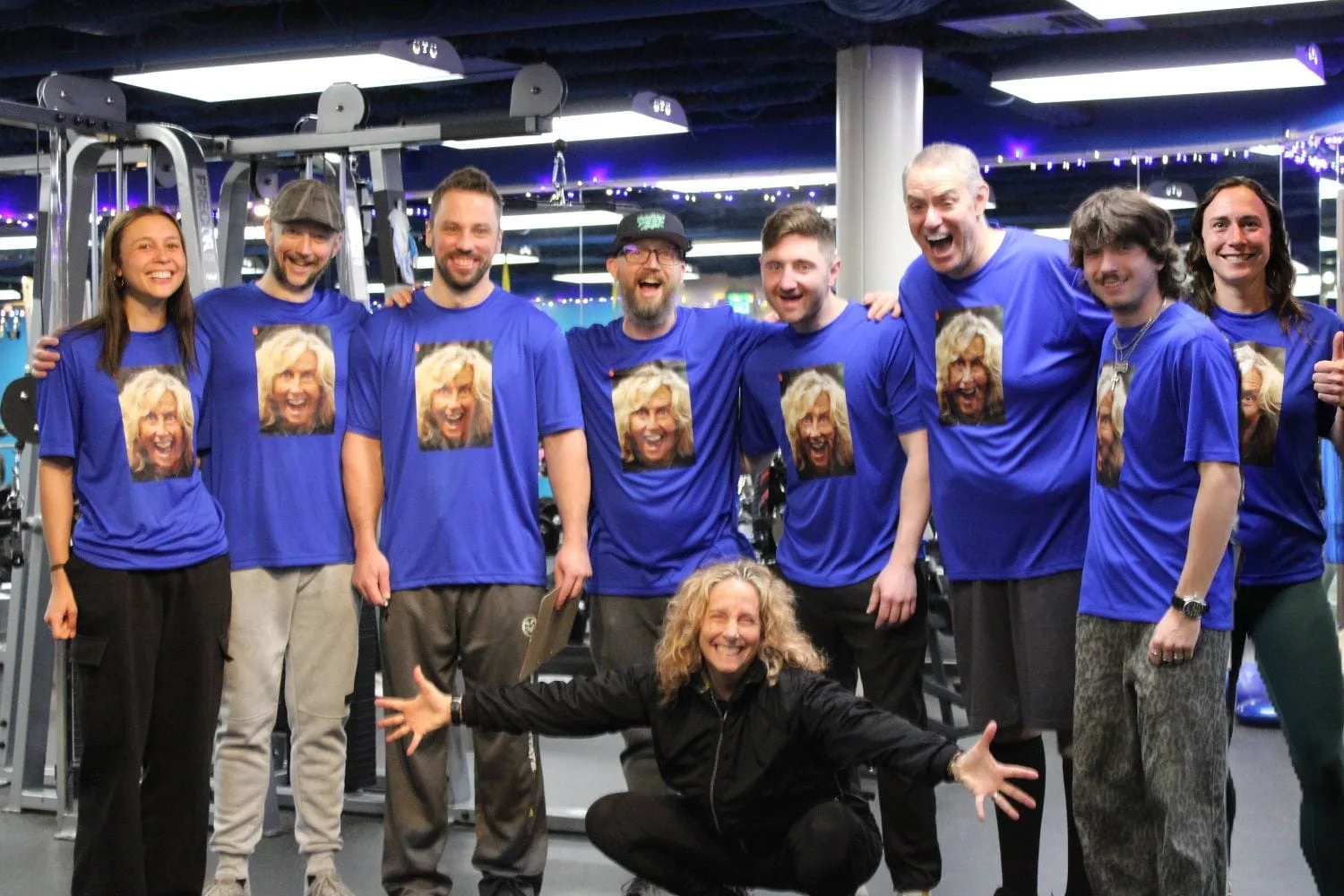 The whole trainer team on the gym floor in shirts printed with the owner’s face